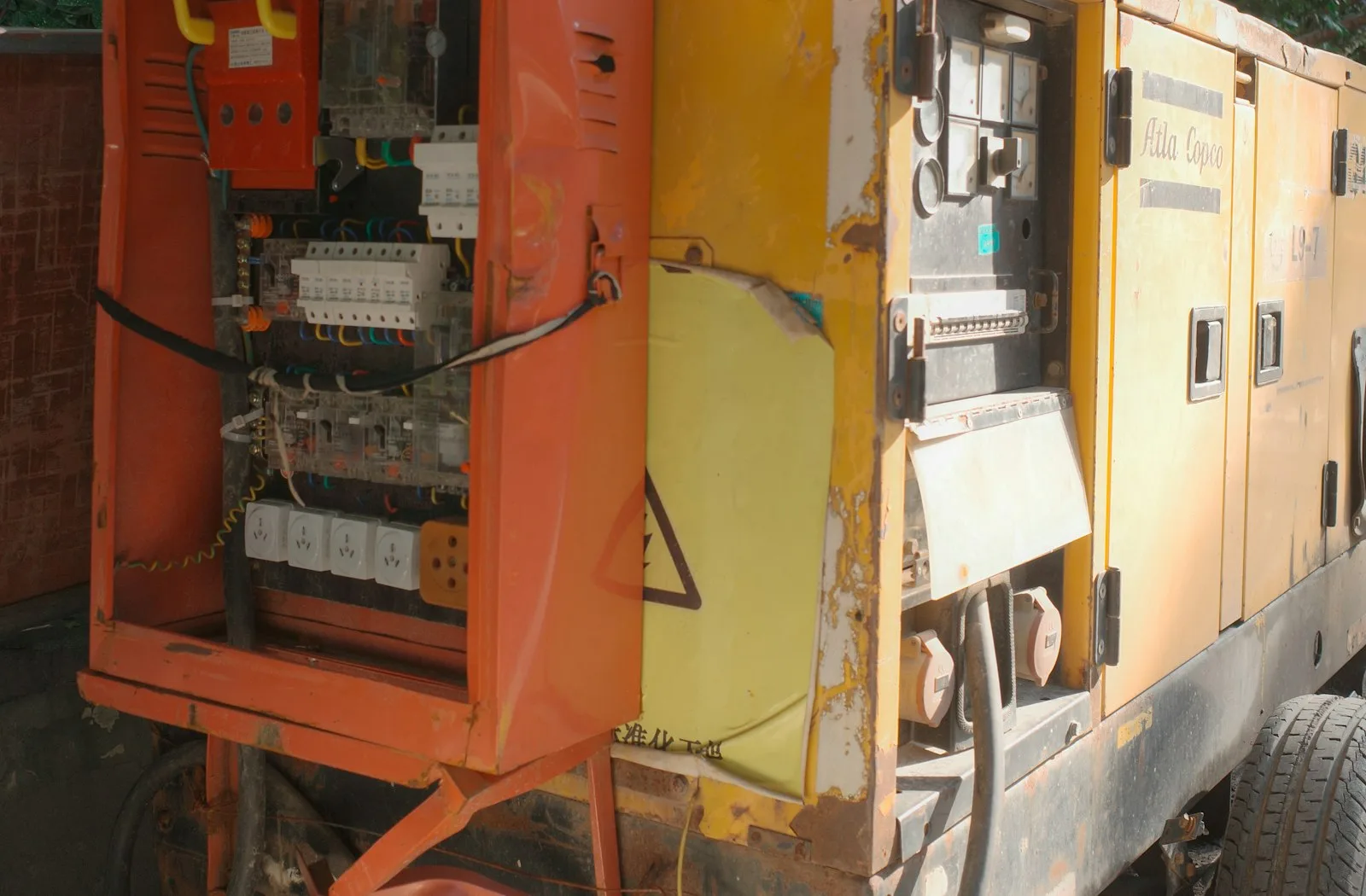 Yellow industrial diesel generator with its electrical panel open for inspection